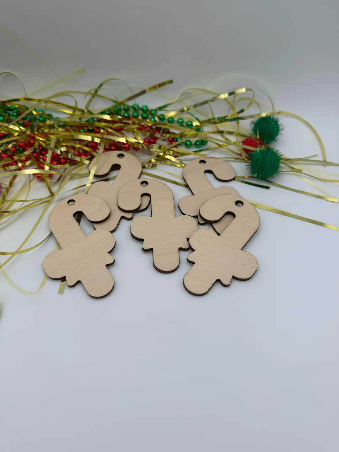 Close view of unfinished wood candy cane ornaments in birch plywood with Christmas ribbon styling
