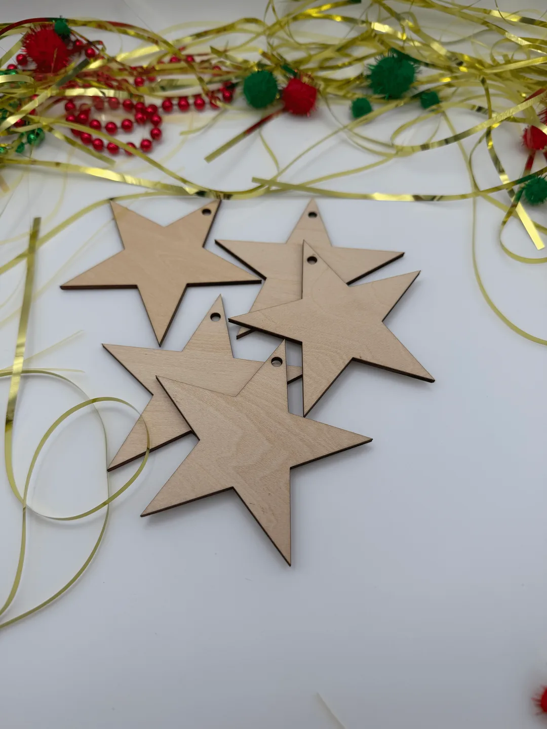 Close view of unfinished wood star ornaments scattered on a white background with Christmas ribbon decor